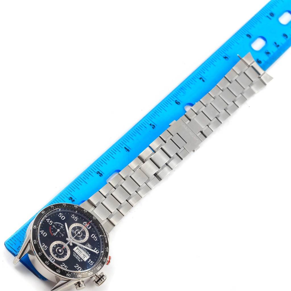 The image shows a Tag Heuer Carrera CV2A10.BA0796 Men's Stainless Steel Black Dial CV2A10.BA0796 Men's Stainless Steel Black Dial watch with a stainless steel bracelet, laid next to a blue ruler for measurement.