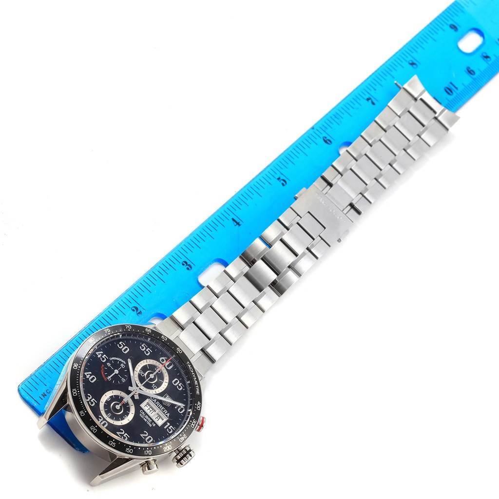 The Tag Heuer Carrera CV2A10.BA0796 Men's Stainless Steel Black Dial CV2A10.BA0796 Men's Stainless Steel Black Dial watch is shown from a top-down angle with a focus on the face and metal bracelet, alongside a blue ruler for measurement.