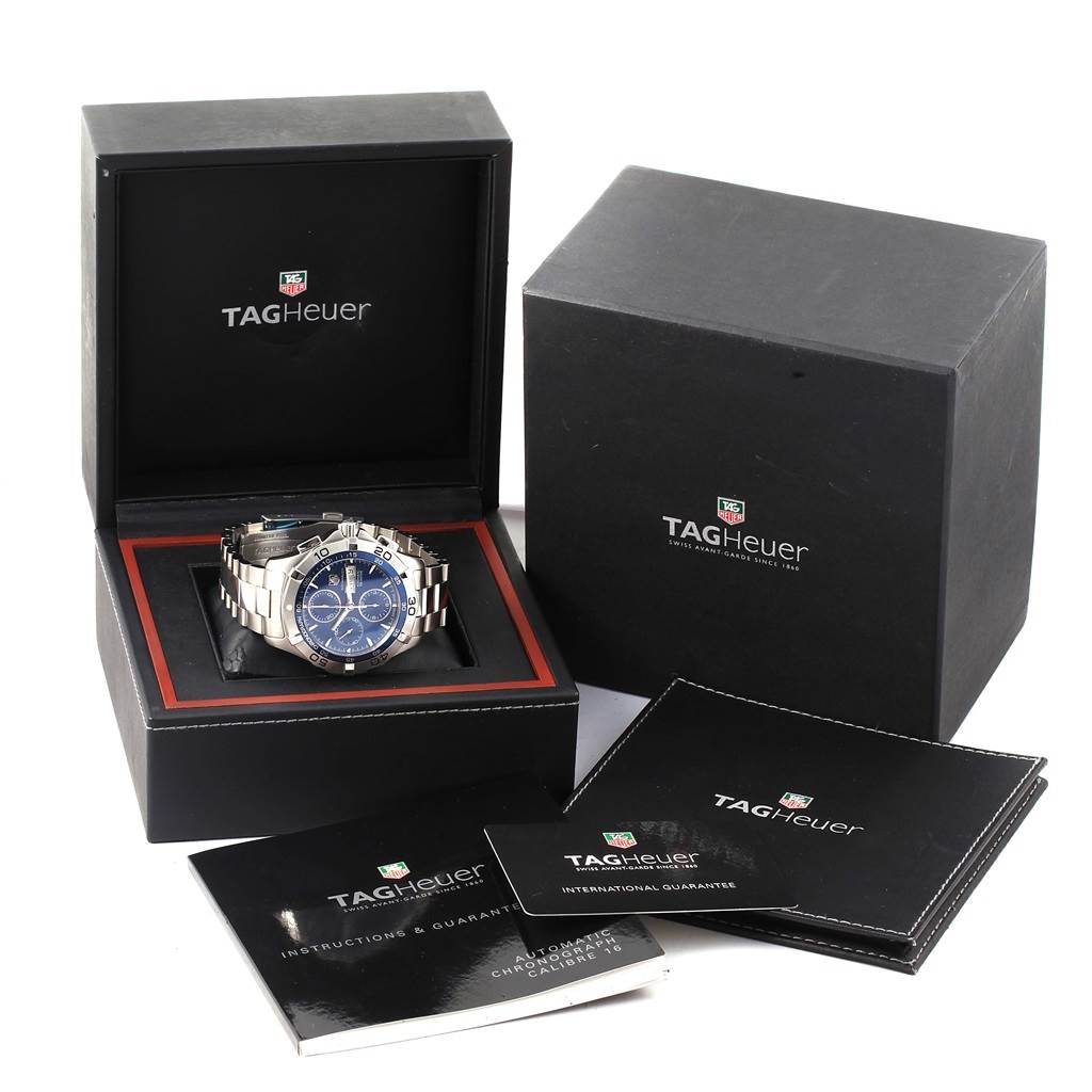 The image shows the Tag Heuer Aquaracer CAF2012.BA0815 Men
s Stainless Steel Blue Dial CAF2012.BA0815 Men
s Stainless Steel Blue Dial watch at an angle with its box, instructions, and guarantee cards.