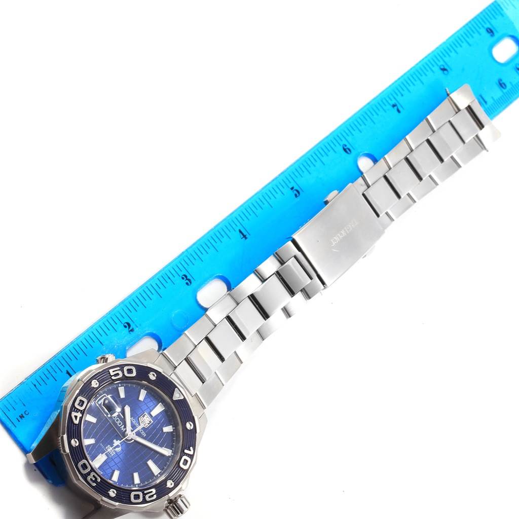 This image shows a Tag Heuer Limited Edition WAJ2116.BA0870 Men's Stainless Steel Blue Dial WAJ2116.BA0870 Men's Stainless Steel Blue Dial watch laid flat with its metal bracelet extended alongside a blue ruler for measurement.