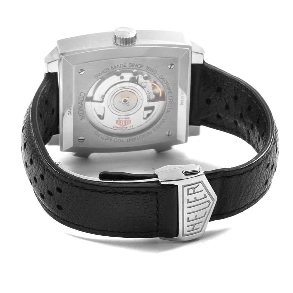 The image shows the back of the Tag Heuer Monaco CAW211P Men's Stainless Steel Blue Dial CAW211P Men's Stainless Steel Blue Dial watch, highlighting its movement and black perforated leather strap with a Heuer clasp.