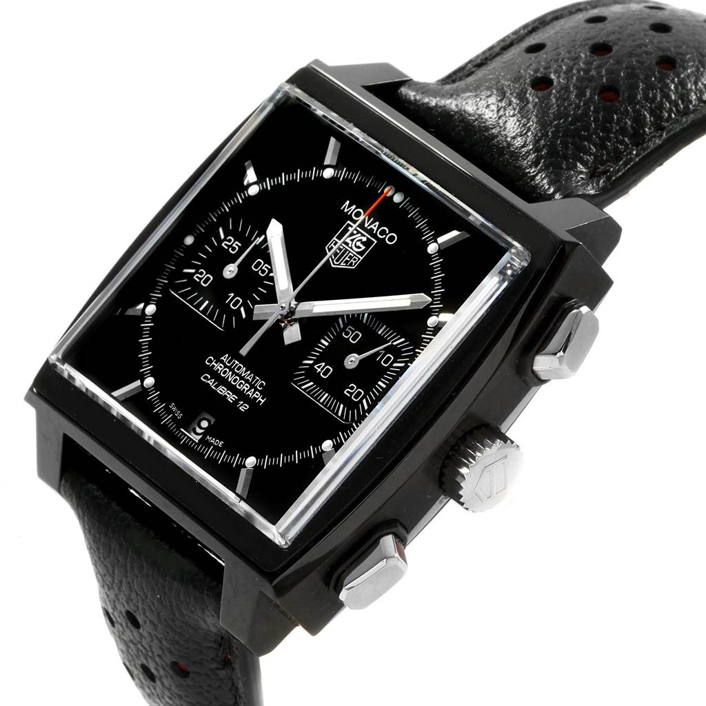 The image shows a Tag Heuer Monaco CAW211M.FC6324 Men's Titanium Black Dial CAW211M.FC6324 Men's Titanium Black Dial watch at an angle revealing its black dial, chronograph subdials, and perforated leather strap.