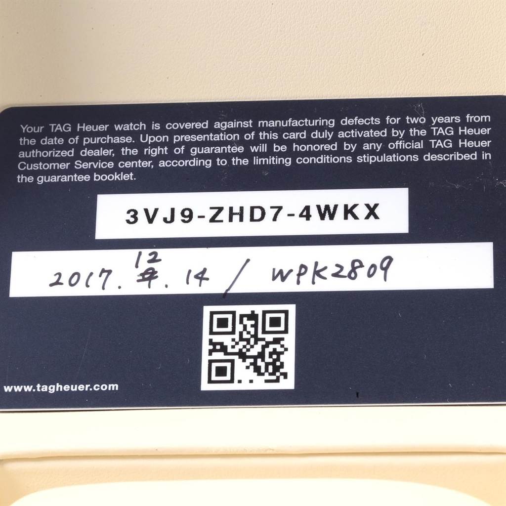 The image shows a close-up of the warranty card for the Carrera model by Tag Heuer, including serial number, date, and QR code.