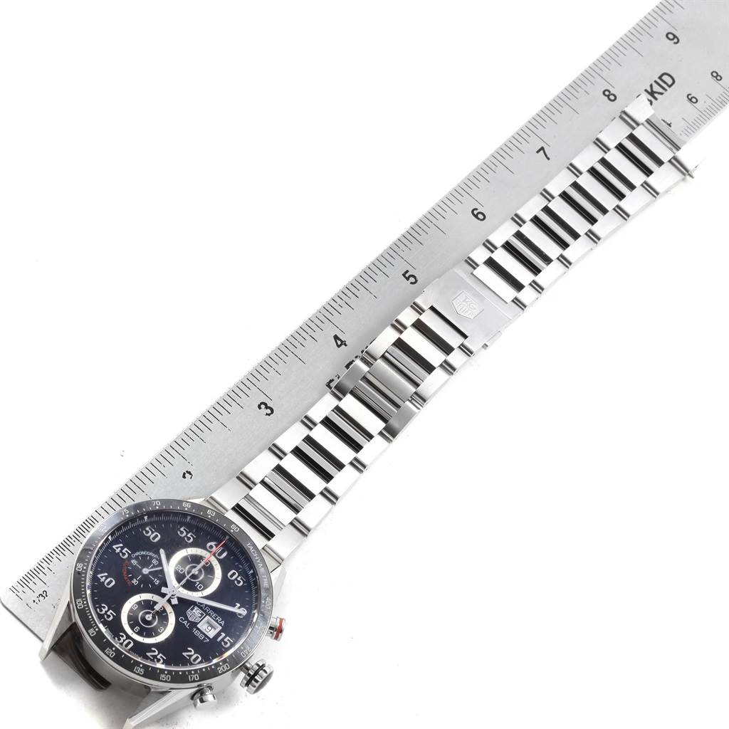 The image shows a top view of a Tag Heuer Carrera CAR2A10.BA0799 Men's Stainless Steel Black Dial CAR2A10.BA0799 Men's Stainless Steel Black Dial watch with a ruler placed alongside its bracelet.