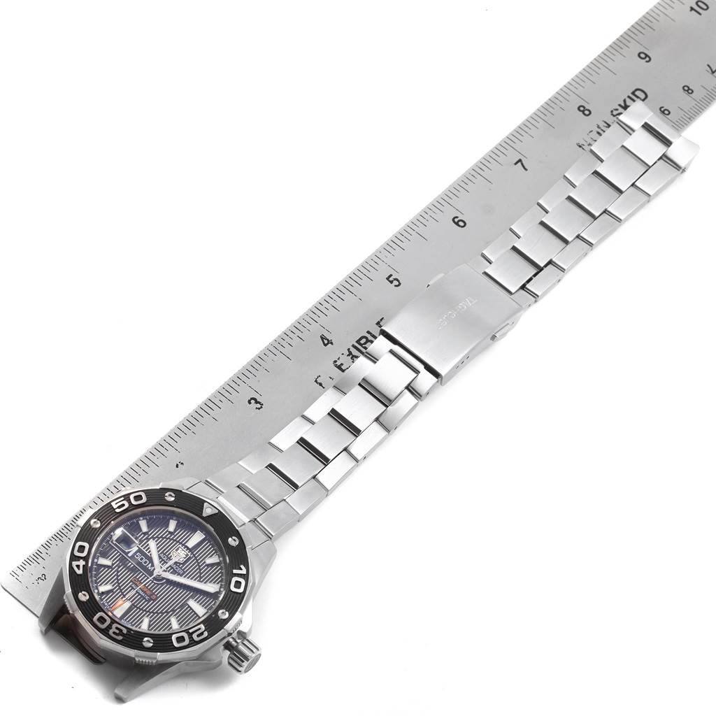 The image shows a Tag Heuer Aquaracer WAJ2110.BA0870 Men
s Stainless Steel Black Dial WAJ2110.BA0870 Men
s Stainless Steel Black Dial watch laid flat next to a ruler, displaying the face, bezel, crown, and the full metal bracelet band.