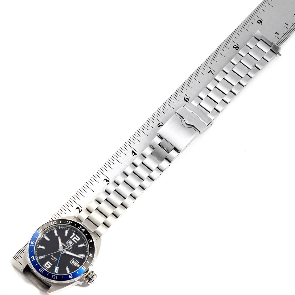 This image shows a Tag Heuer Formula 1 WAZ211A.BA0875 Men's Stainless Steel Black Dial WAZ211A.BA0875 Men's Stainless Steel Black Dial watch with its stainless steel bracelet and clasp, angled on a ruler for measurement.