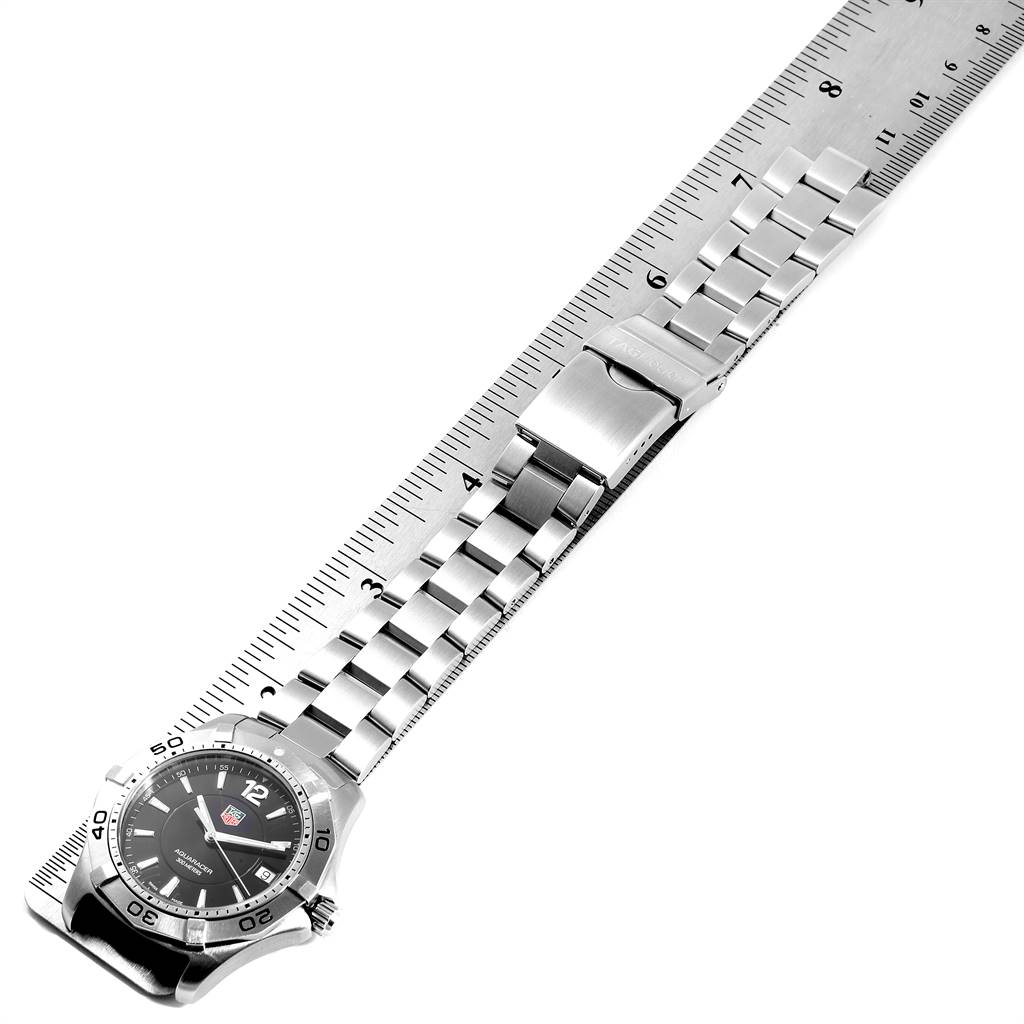 The image shows a Tag Heuer Aquaracer WAF1110.BA0800 Men's Stainless Steel Black Dial WAF1110.BA0800 Men's Stainless Steel Black Dial watch laid flat against a ruler, displaying the full metal band and clasp.