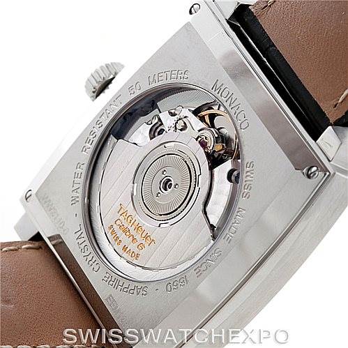 The image shows the back casing and internal mechanism of a Tag Heuer Monaco WW2110 Men's Stainless Steel Black Dial WW2110 Men's Stainless Steel Black Dial watch at an angle revealing its movement and engravings.