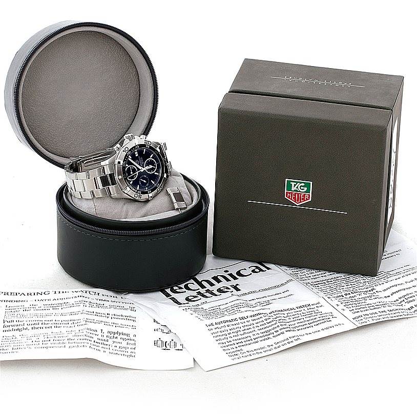 The image shows a Tag Heuer Aquaracer CAF2110 Men's Stainless Steel Black Dial CAF2110 Men's Stainless Steel Black Dial watch resting in an open circular case, accompanied by a box and instruction papers.
