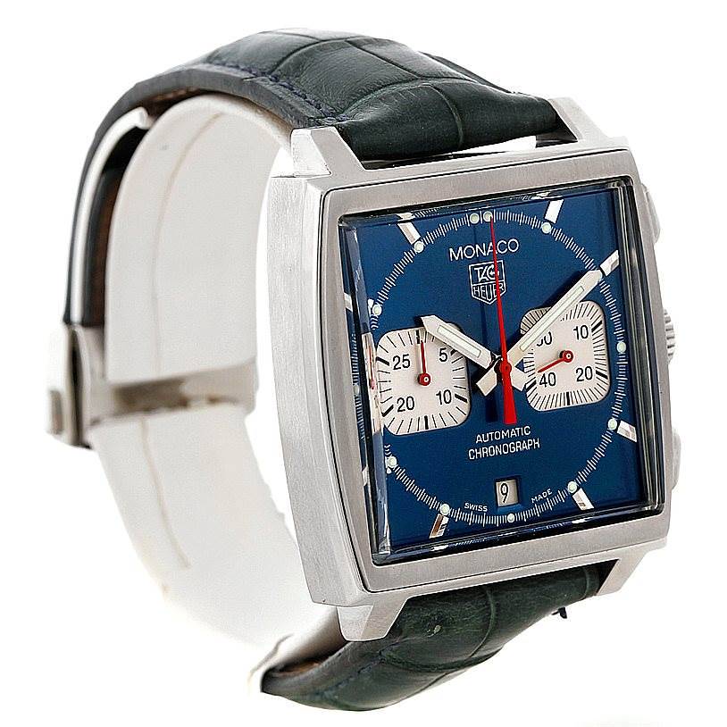 The Tag Heuer Monaco watch is shown from a front angle, highlighting its square face, blue dial, sub-dials, and leather strap.