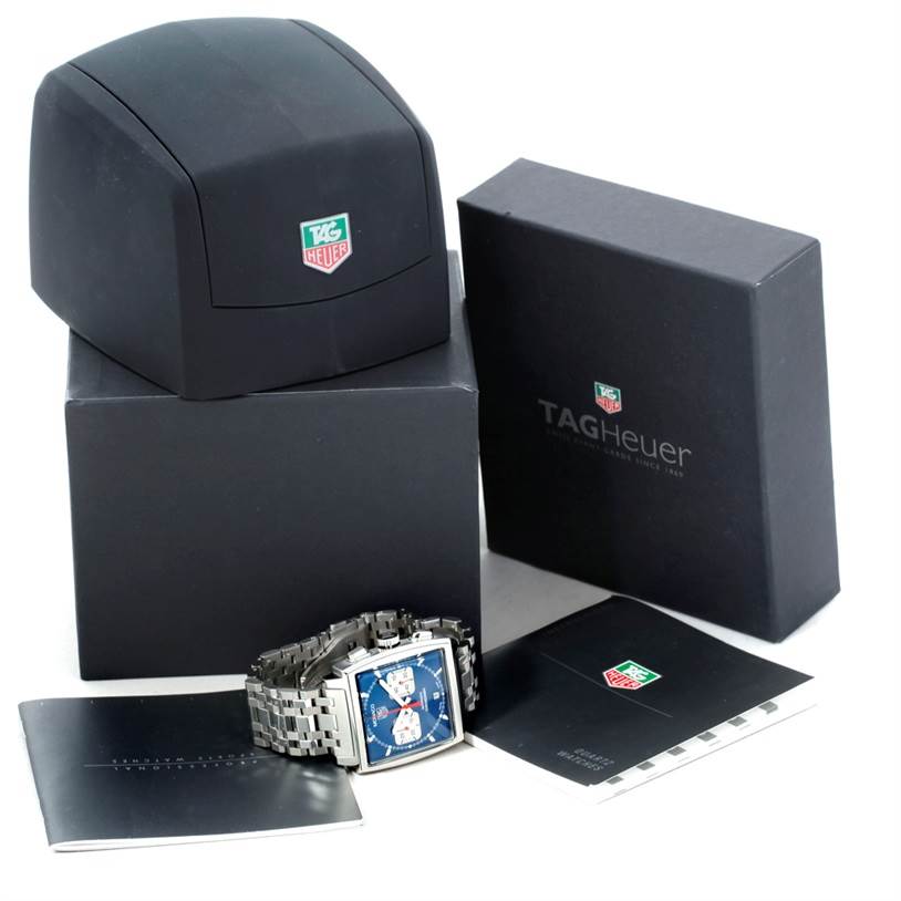 The image shows a Tag Heuer Monaco CW2113 Men's Stainless Steel Blue Dial CW2113 Men's Stainless Steel Blue Dial watch with its case, box, and accompanying booklets placed at a slight angle.