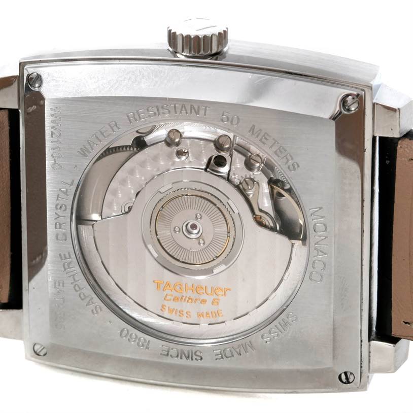 The image shows the back of a Tag Heuer Monaco WW2110 Men's Stainless Steel Black Dial WW2110 Men's Stainless Steel Black Dial watch, displaying its exposed movement and engraved details.