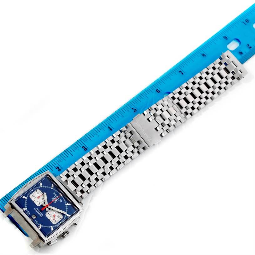 The Tag Heuer Monaco CW2113 Men's Stainless Steel Blue Dial CW2113 Men's Stainless Steel Blue Dial watch is displayed horizontally with a blue dial, square case, and steel bracelet measured against a blue ruler.