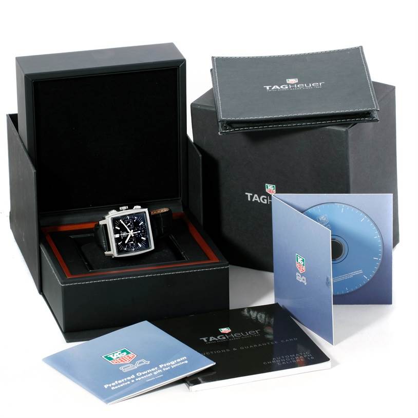 The image shows a Tag Heuer Monaco CW2111 Men
s Stainless Steel Black Dial CW2111 Men
s Stainless Steel Black Dial watch in its open box, along with booklets, a CD, and the outer packaging.