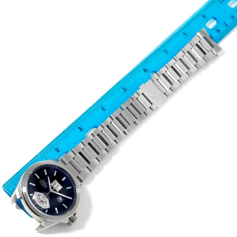 The image shows a Tag Heuer Carrera WAV5111 Men
s Stainless Steel Black Dial WAV5111 Men
s Stainless Steel Black Dial model watch laid flat next to a blue ruler, displaying the watch face and metal bracelet.