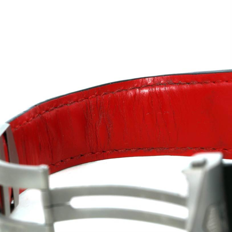 The image shows a close-up of the red leather interior and metal clasp of a Tag Heuer Carrera CAV5185.FC6237 Men's Titanium Black Dial CAV5185.FC6237 Men's Titanium Black Dial watch strap.