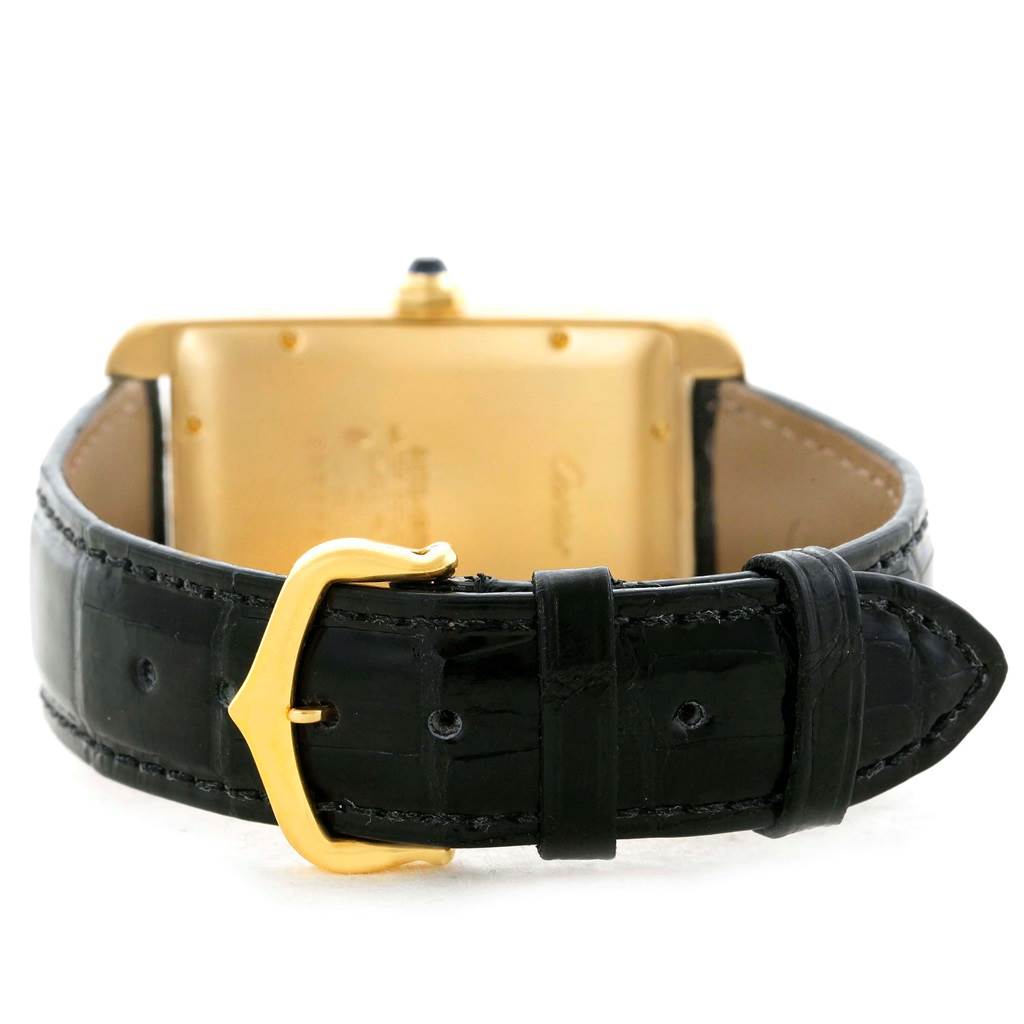 The image shows the back of a Cartier Tank Americaine W2603156 Men's Yellow Gold Silver Dial W2603156 Men's Yellow Gold Silver Dial watch, focusing on its black leather strap and gold buckle.