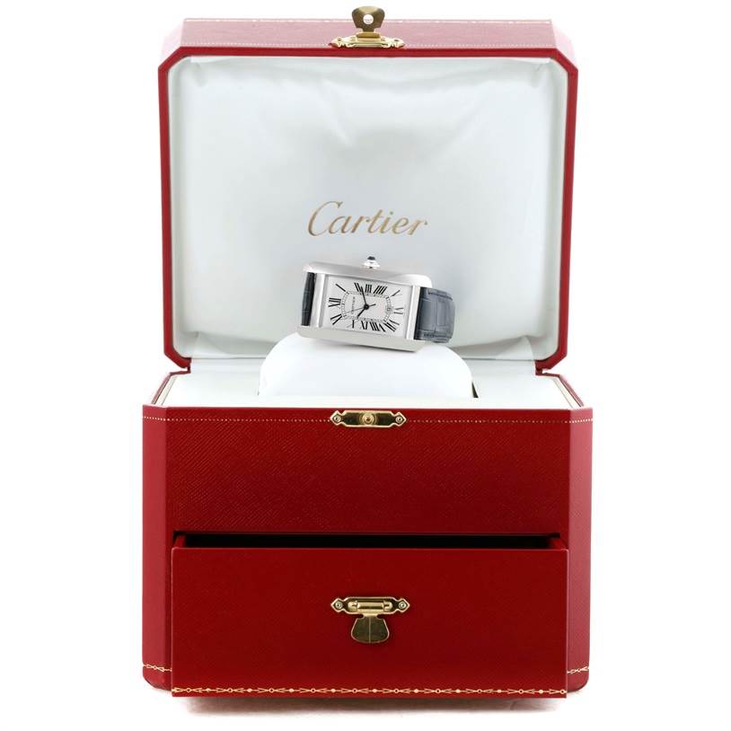 The Cartier Tank Américaine watch is shown in a red presentation box, displaying the face and strap from a front angle.