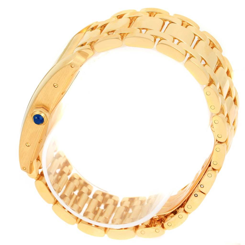 This image shows a side profile and partial view of the bracelet of a Cartier Tank Americaine W26031K2 Men
s Yellow Gold Silver Dial W26031K2 Men
s Yellow Gold Silver Dial watch, highlighting its gold links and blue cabochon crown.