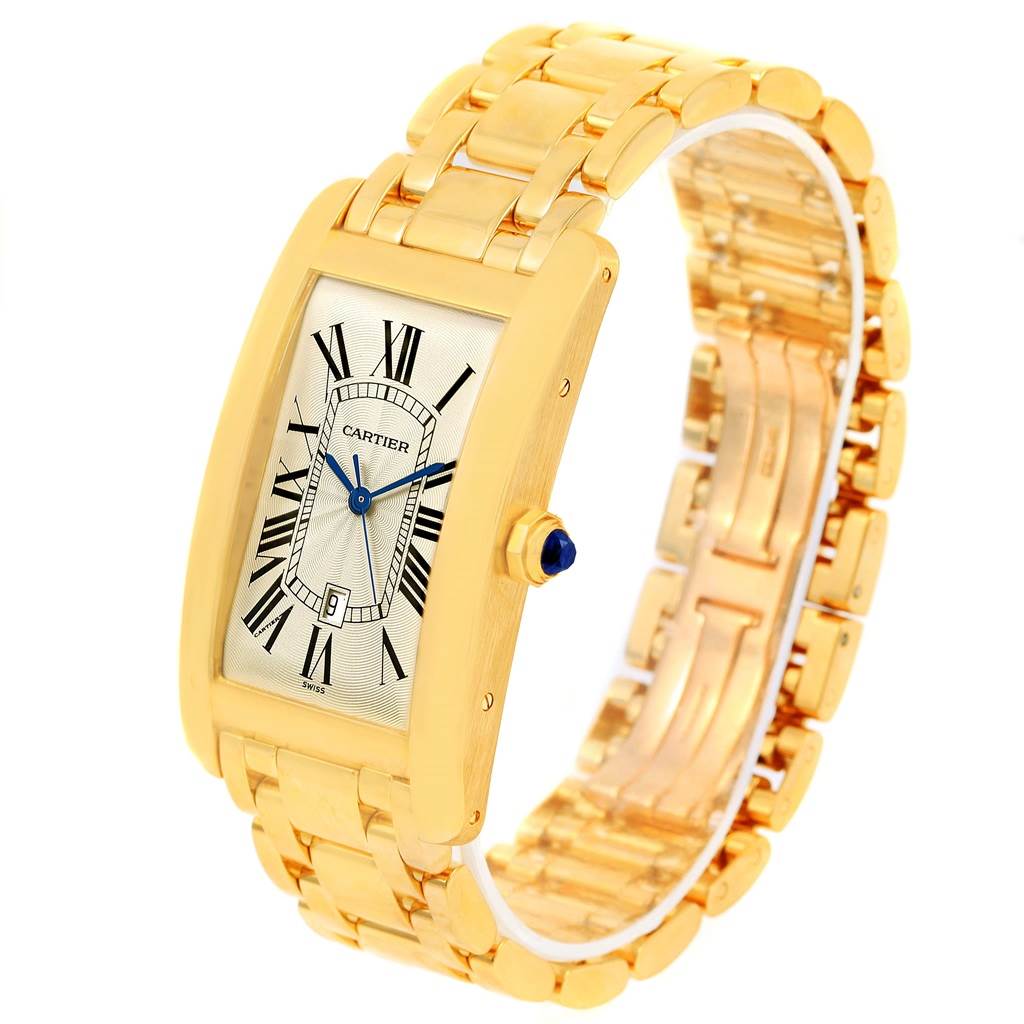 The image shows a Cartier Tank Americaine W26031K2 Men
s Yellow Gold Silver Dial W26031K2 Men
s Yellow Gold Silver Dial watch from an angled front view, highlighting its gold case and bracelet.