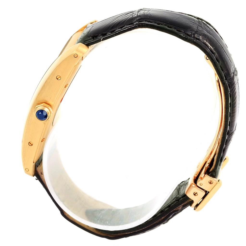 The image shows a side view of the Cartier Tank Américaine watch, highlighting its gold case, crown with blue cabochon, and black leather strap.