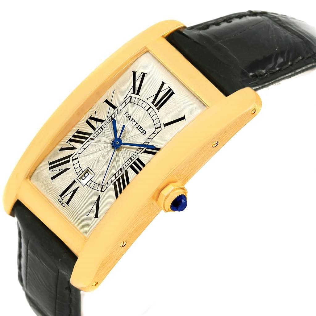 The Cartier Tank Americaine W2603156 Men's Yellow Gold Silver Dial W2603156 Men's Yellow Gold Silver Dial watch is shown at an angle showcasing its gold case, rectangular dial, blue hands, and black leather strap.