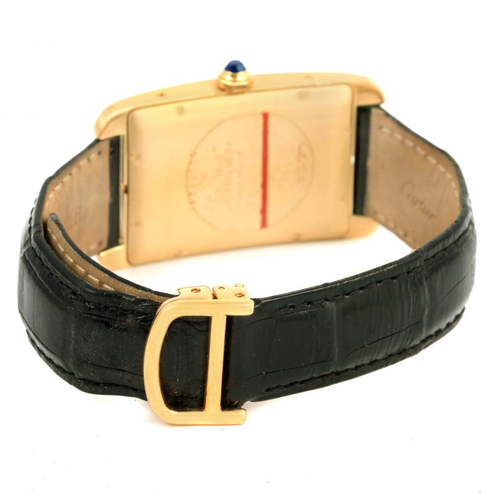 The image shows the Tank Americaine model by Cartier from the back, highlighting its gold case, black leather strap, and gold buckle.