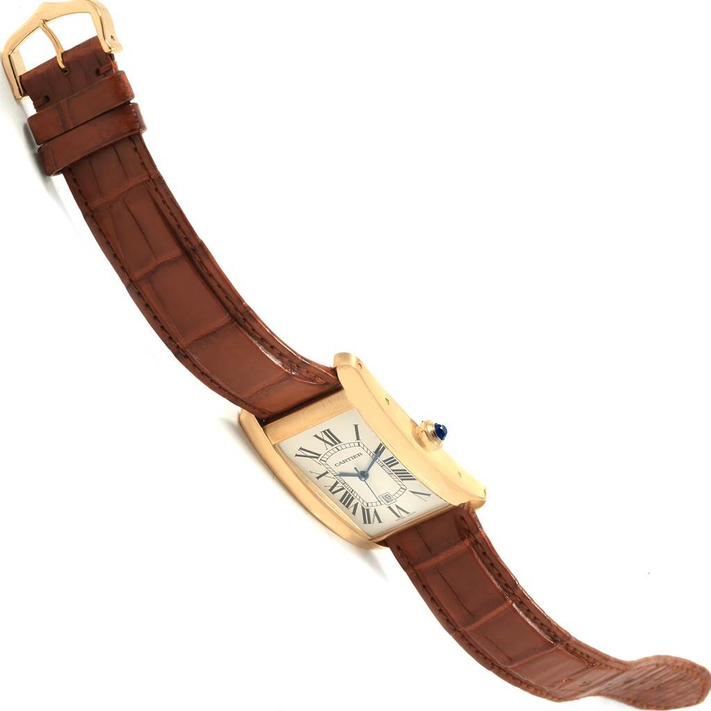This image shows the Cartier Tank Americaine W2603156 Men's Yellow Gold Silver Dial W2603156 Men's Yellow Gold Silver Dial watch from a side angle displaying the face, crown, and leather strap.