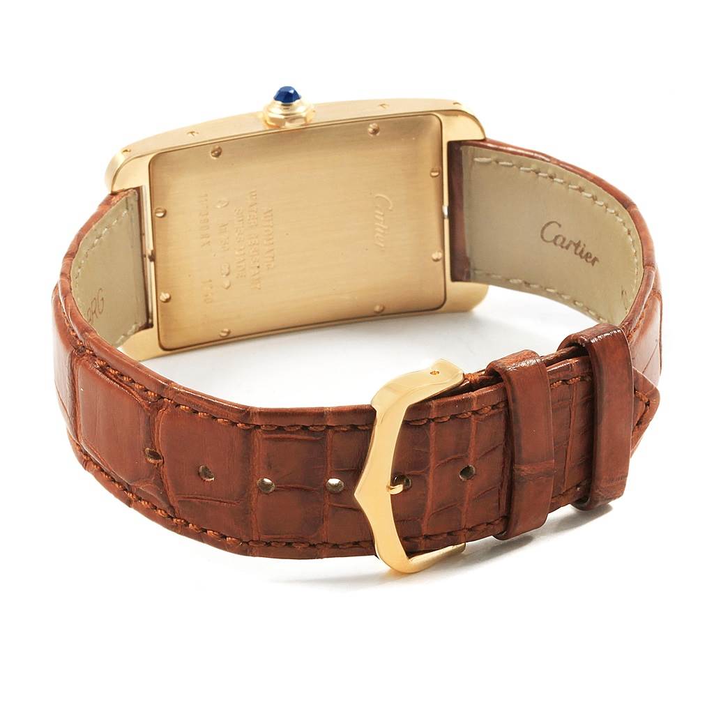 The Cartier Tank Americaine W2603156 Men's Yellow Gold Silver Dial W2603156 Men's Yellow Gold Silver Dial watch is shown from the rear, highlighting its gold case back, crown, and brown leather strap.