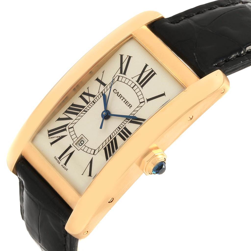 The Tank Americaine watch by Cartier is shown at a 3/4 angle, displaying the face, date window, gold casing, and leather strap.
