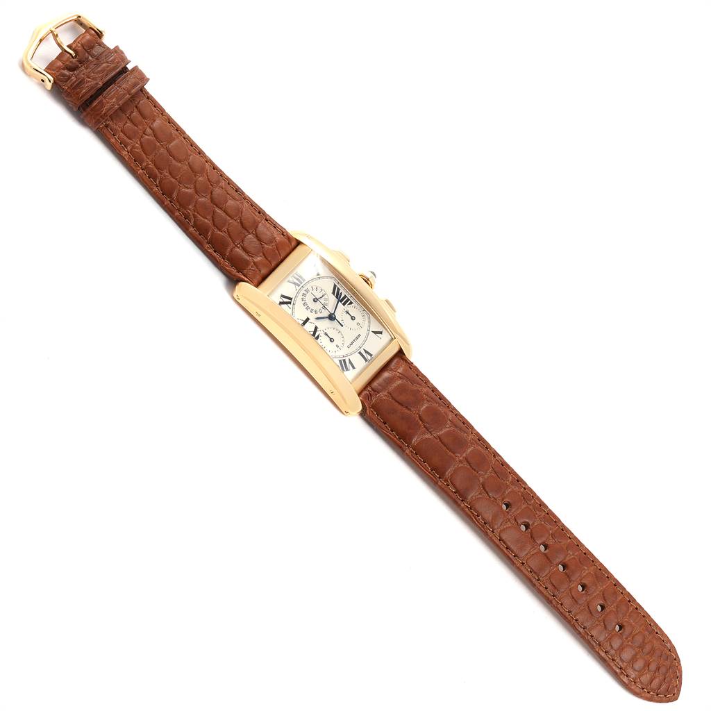 The image shows a top-down view of a Cartier Tank Americaine W2601156 Men's Yellow Gold Silver Dial W2601156 Men's Yellow Gold Silver Dial watch, displaying the face, case, crown, and brown leather strap.