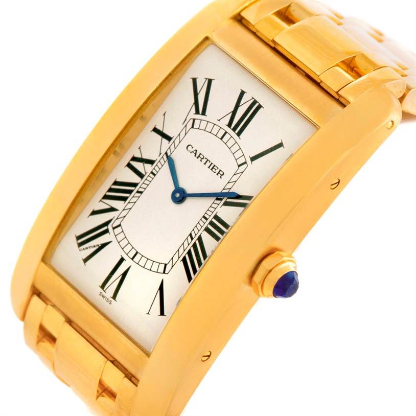 This image shows a close-up angle of the Cartier Tank Americaine 1735 Men
s Yellow Gold Silver Dial 1735 Men
s Yellow Gold Silver Dial watch, highlighting its face, crown, and partial bracelet.