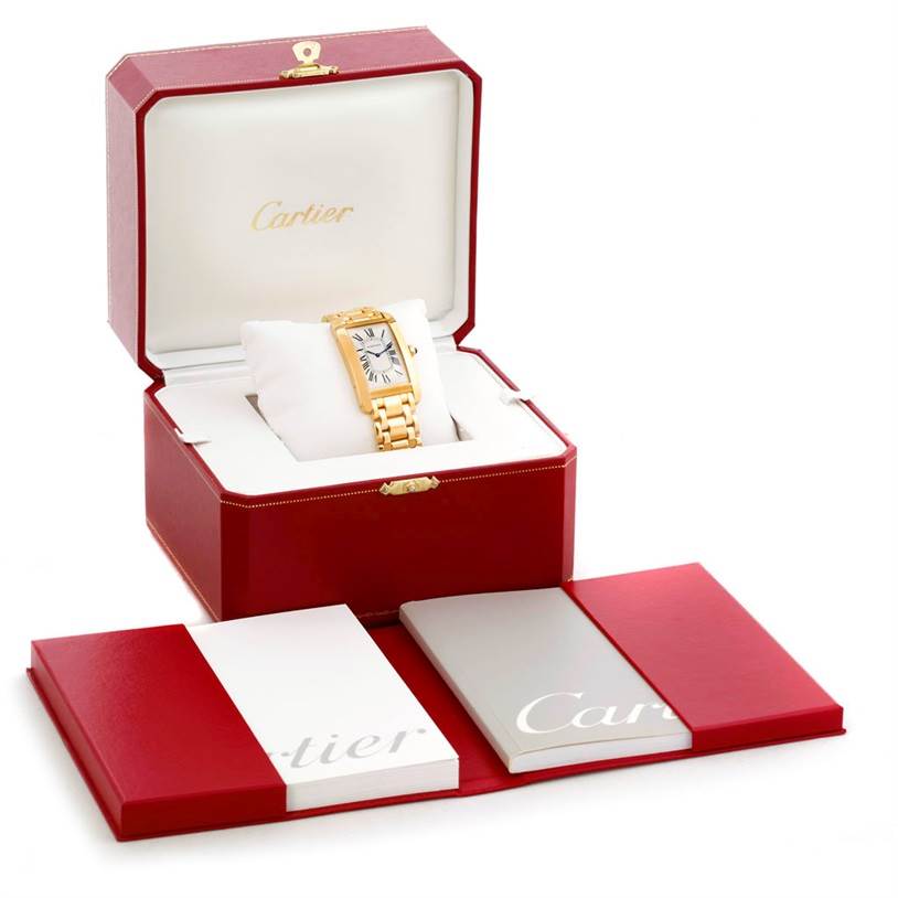 The image shows a Cartier Tank Americaine 1735 Men
s Yellow Gold Silver Dial 1735 Men
s Yellow Gold Silver Dial watch in its open red box, with booklets laid out in front.