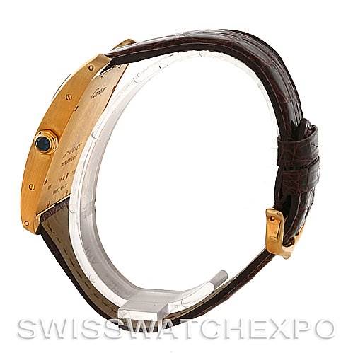 This image shows a side view of the Cartier Tank Américaine watch, highlighting its gold case, a crown with a blue cabochon, and brown leather strap.