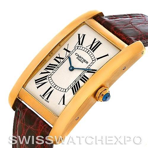 The image shows a Cartier Tank Americaine Yellow Gold Silver Dial Yellow Gold Silver Dial watch at an angle highlighting the gold case, Roman numeral dial, and part of the leather strap.