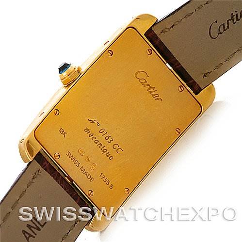 The image shows the back case and leather straps of a Cartier Tank Americaine Yellow Gold Silver Dial Yellow Gold Silver Dial watch, highlighting its serial number and "Swiss Made" inscription.