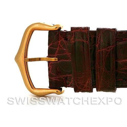 This image shows a close-up of the gold buckle and maroon leather strap of a Cartier Tank Americaine Yellow Gold Silver Dial Yellow Gold Silver Dial watch.