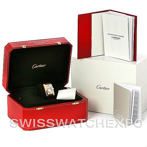 The image shows the Cartier Tank Américaine watch inside its open red case, with accompanying booklets and a white outer box.