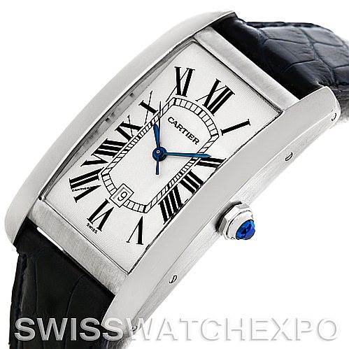 The image shows a Cartier Tank Américaine watch angled slightly to display its rectangular face, Roman numerals, blue hands, and crown with a blue jewel.