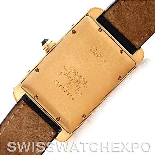 The image shows the back case of a Cartier Tank Américaine watch, highlighting its engravings and leather strap.