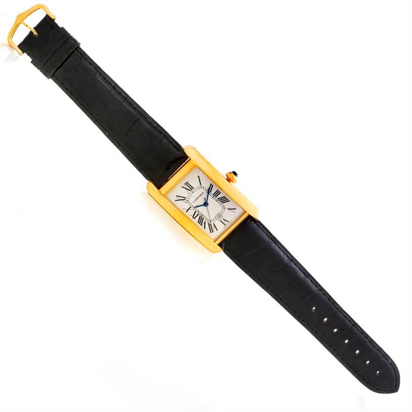 The Cartier Tank Americaine W2603156 Men's Yellow Gold Silver Dial W2603156 Men's Yellow Gold Silver Dial watch is shown from a top-down angle, displaying its rectangular case, black leather strap, and dial.