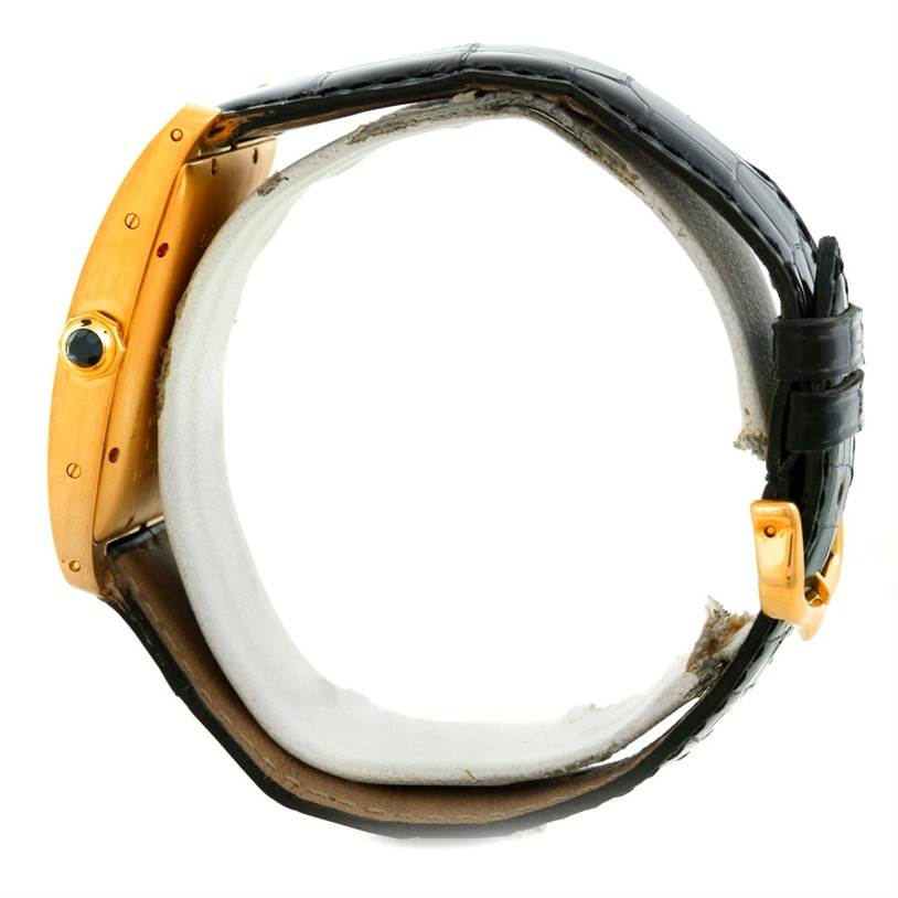 The image shows a side view of the Cartier Tank Americaine W2603156 Men's Yellow Gold Silver Dial W2603156 Men's Yellow Gold Silver Dial watch, highlighting its case, crown, and alligator leather strap.