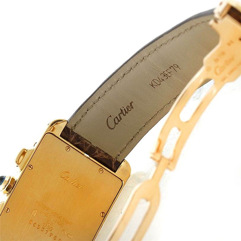 This image shows the back case and part of the leather strap of a Cartier Tank Americaine W2605856 Men's Yellow Gold Silver Dial W2605856 Men's Yellow Gold Silver Dial watch, highlighted by the brand's engraving.