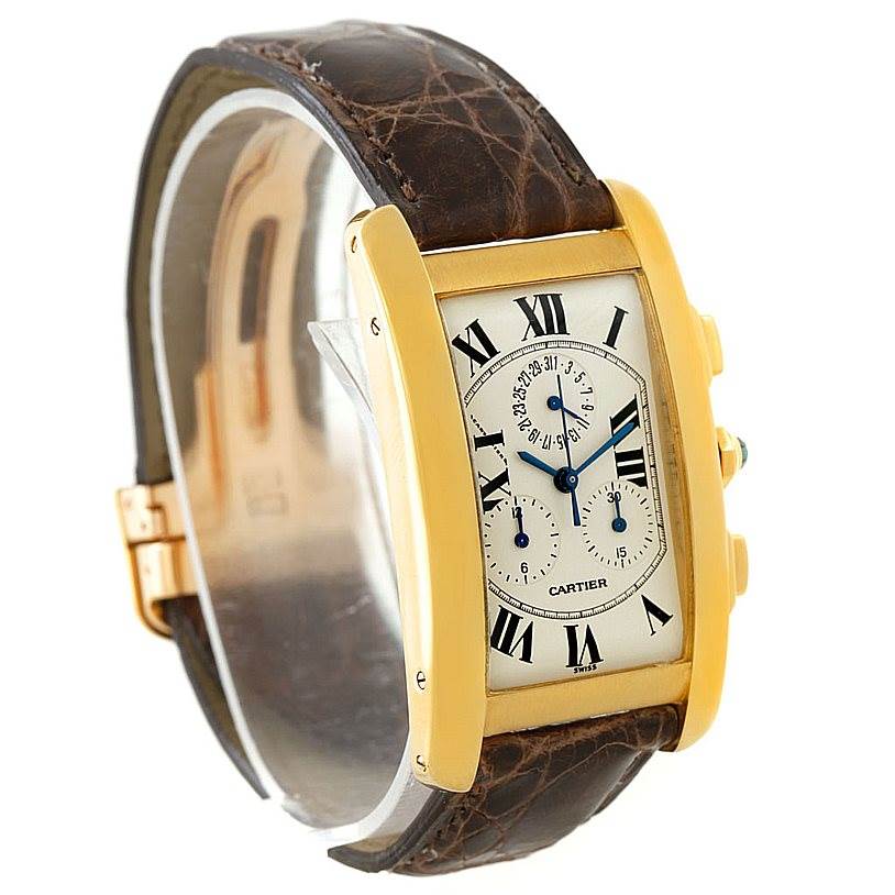 The image shows a Cartier Tank Americaine W2605856 Men's Yellow Gold Silver Dial W2605856 Men's Yellow Gold Silver Dial watch from an angled side view, highlighting the face, strap, and side buttons.