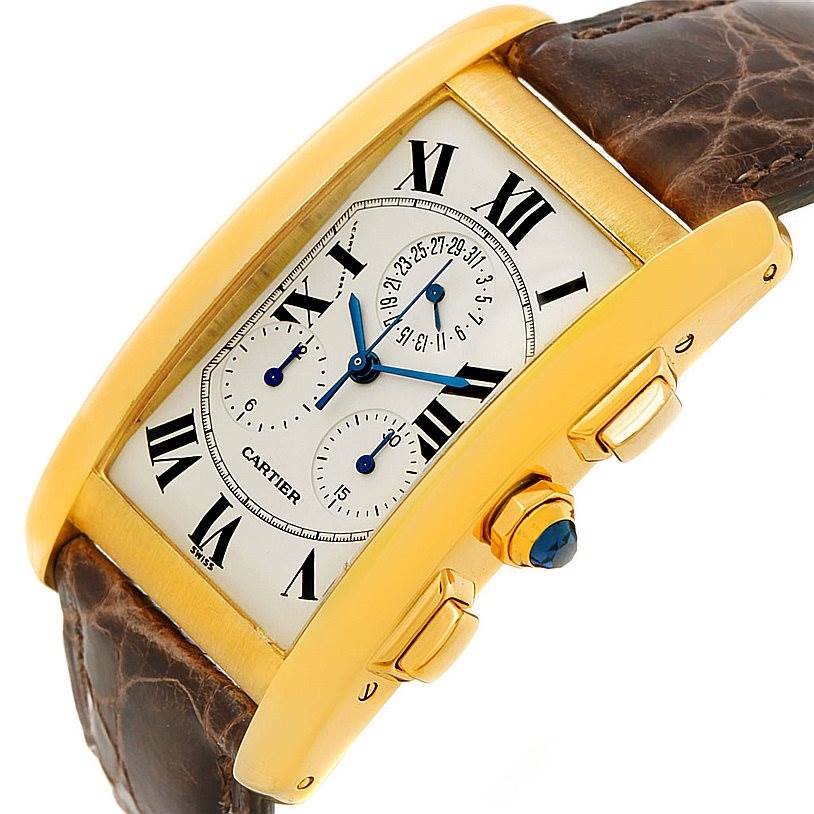 The image shows a close-up angled view of a Cartier Tank Americaine W2605856 Men's Yellow Gold Silver Dial W2605856 Men's Yellow Gold Silver Dial watch, highlighting its dial, case, crown, and brown leather strap.