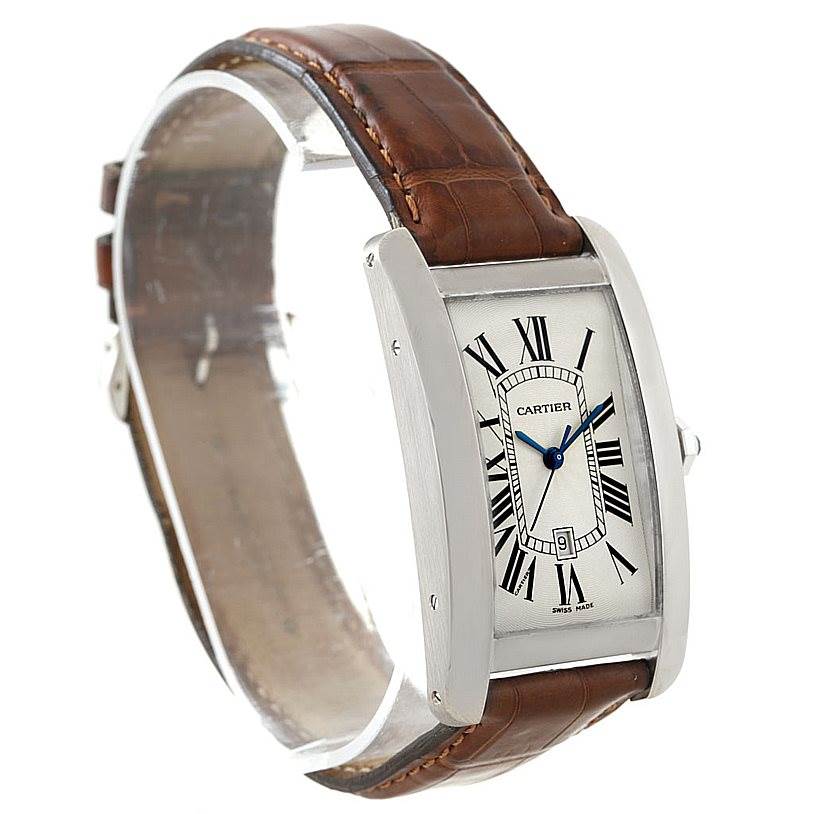 The image shows the Cartier Tank Americaine W2603256 Men's White Gold Silver Dial W2603256 Men's White Gold Silver Dial watch at a three-quarter angle, highlighting its brown leather strap and rectangular face.