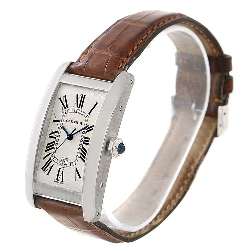 The watch is a Cartier Tank Americaine W2603256 Men's White Gold Silver Dial W2603256 Men's White Gold Silver Dial with a silver dial, brown leather strap, and visible crown, angled slightly from the front and side.