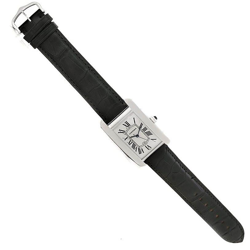 The image shows a Cartier Tank Americaine W2603256 Men
s White Gold Silver Dial W2603256 Men
s White Gold Silver Dial watch with a black leather strap, silver rectangular face, and Roman numerals, viewed from above.