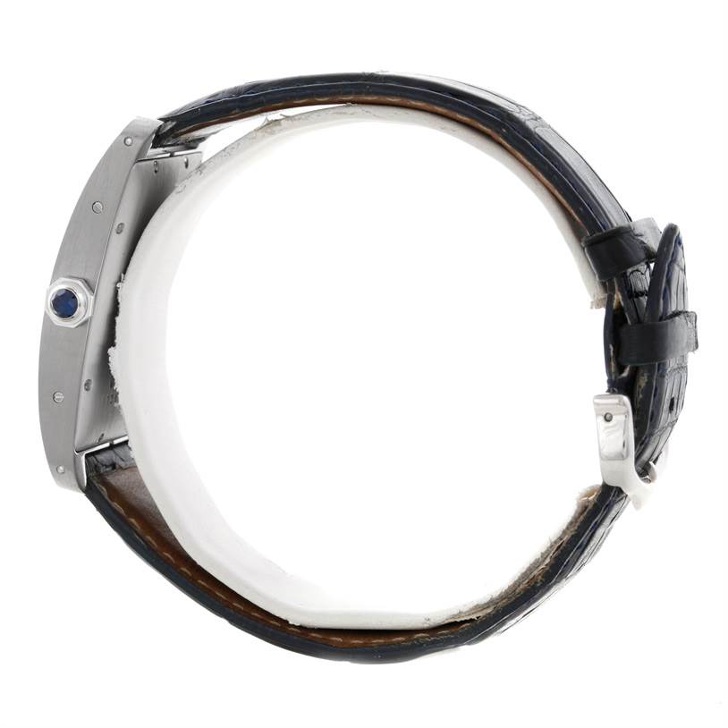 This image shows a side view of the Cartier Tank Américaine watch, highlighting its strap, buckle, and crown with a blue stone.