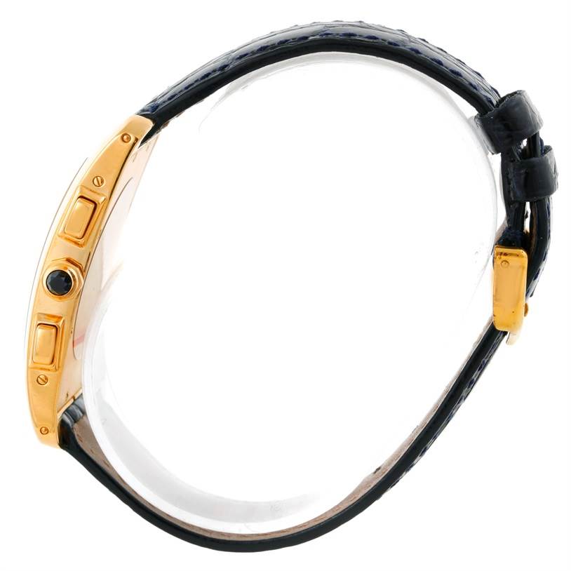 The image shows a Cartier Tank Americaine W2601156 Men
s Yellow Gold Silver Dial W2601156 Men
s Yellow Gold Silver Dial watch from a side angle, highlighting the gold case, crown, and strap.